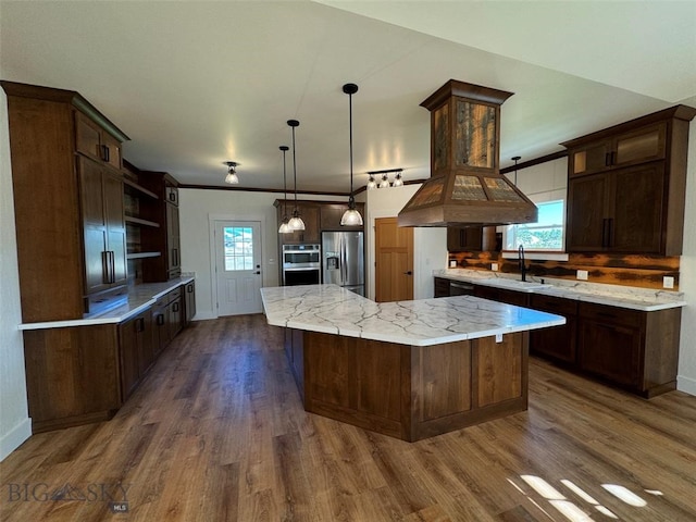 kitchen featuring appliances with stainless steel finishes, dark wood-type flooring, pendant lighting, a large island, and sink