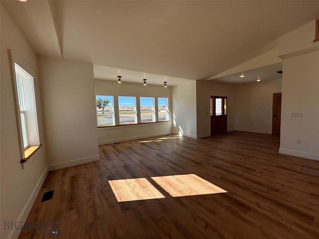 empty room featuring vaulted ceiling and dark hardwood / wood-style flooring