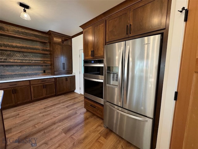 kitchen featuring appliances with stainless steel finishes, dark brown cabinetry, and light hardwood / wood-style flooring