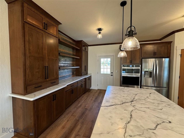 kitchen with pendant lighting, dark wood-type flooring, appliances with stainless steel finishes, ornamental molding, and light stone countertops