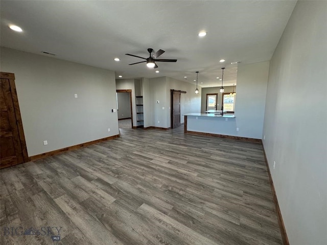 unfurnished living room with ceiling fan and dark wood-type flooring