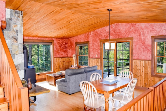 dining area with wood ceiling, a wealth of natural light, vaulted ceiling, and a wood stove