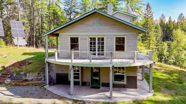 rear view of house with a wooden deck and a patio