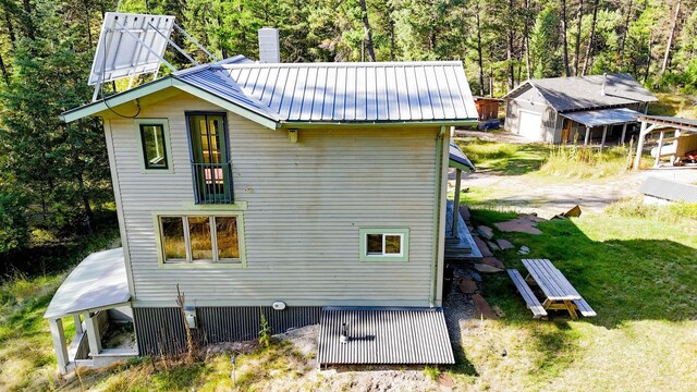 back of house with a lawn, a sunroom, a patio, and solar panels