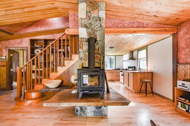 dining space featuring wood ceiling, lofted ceiling, light hardwood / wood-style flooring, and a wood stove