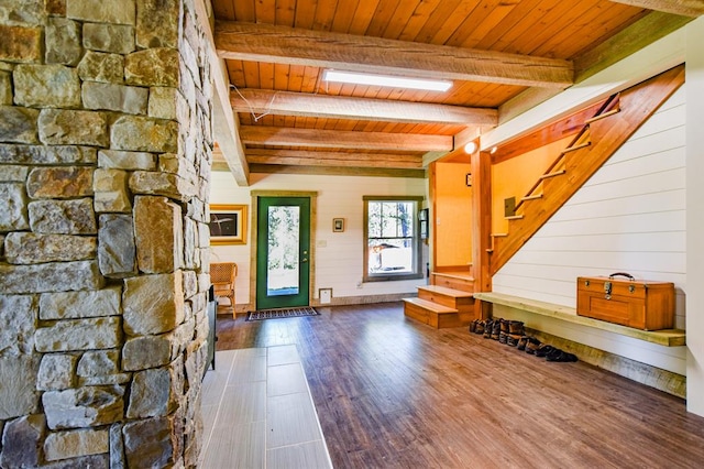 foyer entrance with hardwood / wood-style flooring, beam ceiling, a skylight, wooden walls, and wooden ceiling