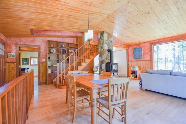 dining room with vaulted ceiling, a wood stove, wooden ceiling, and light wood-type flooring