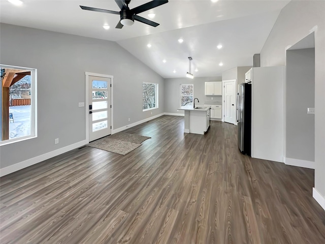 unfurnished living room with sink, vaulted ceiling, dark hardwood / wood-style floors, and ceiling fan