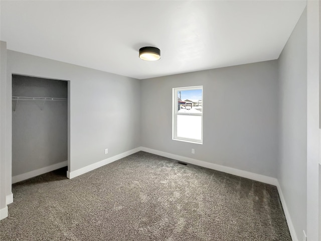 unfurnished bedroom featuring dark carpet and a closet