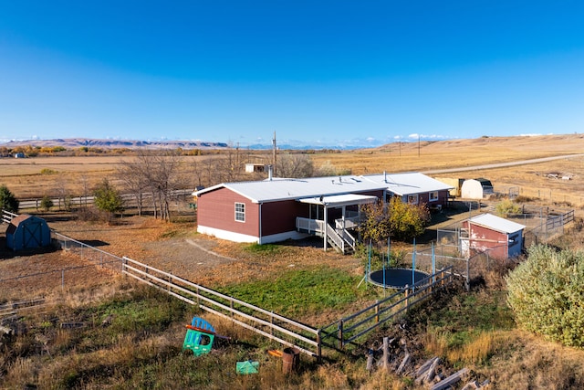 back of house featuring an outdoor structure and a rural view