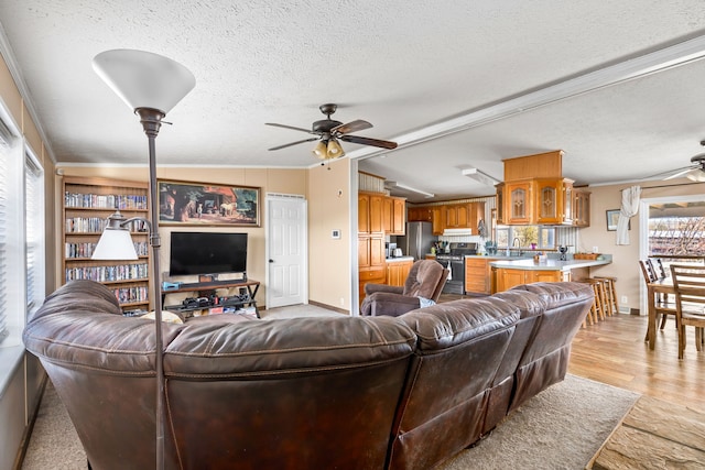 living room with vaulted ceiling, ornamental molding, a textured ceiling, and ceiling fan