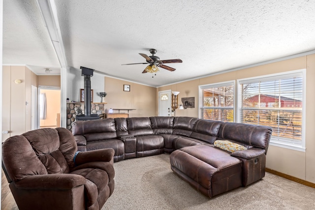 carpeted living room with ceiling fan, ornamental molding, a textured ceiling, and a wood stove