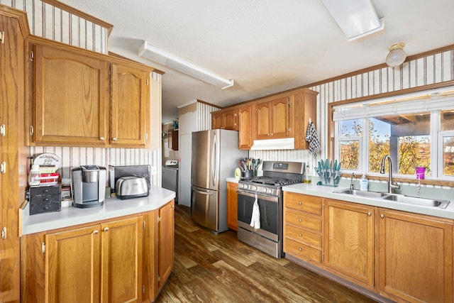 kitchen featuring sink, dark wood-type flooring, stainless steel appliances, a textured ceiling, and washer / dryer