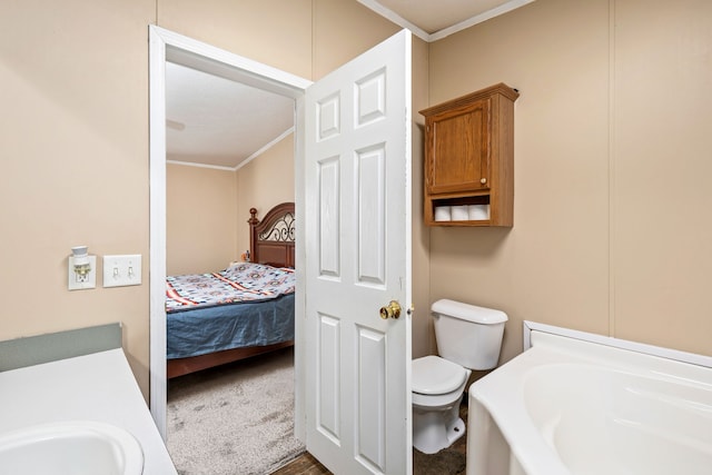 bathroom featuring ornamental molding, toilet, sink, and a washtub