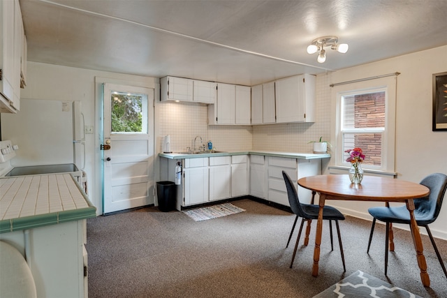 kitchen with sink, white cabinetry, stove, decorative backsplash, and tile countertops