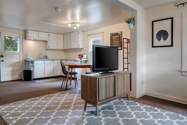 kitchen with backsplash, white cabinetry, sink, and dark carpet