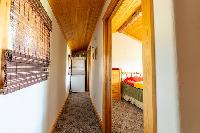 corridor with dark colored carpet, vaulted ceiling, and wooden ceiling