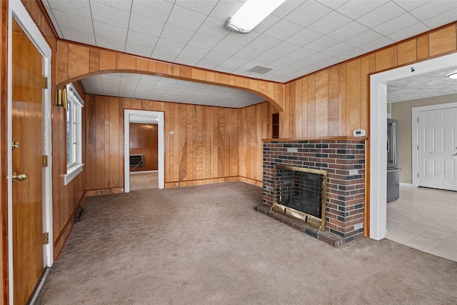 161 3rd Ave, Kalispell, MT 59901 - unfurnished living room with wooden walls, carpet flooring, arched walkways, and a fireplace
