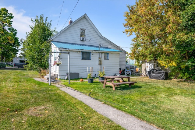 back of property with metal roof and a lawn