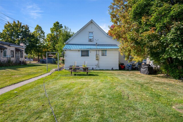 back of house with metal roof and a lawn