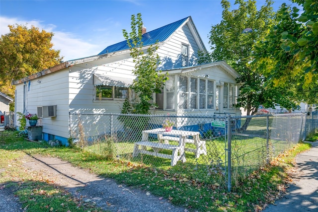 view of front of house featuring a chimney, metal roof, a sunroom, and fence private yard