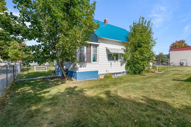 back of house with a yard, a chimney, metal roof, and fence