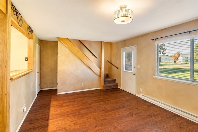 spare room with baseboards, wood finished floors, stairway, and baseboard heating