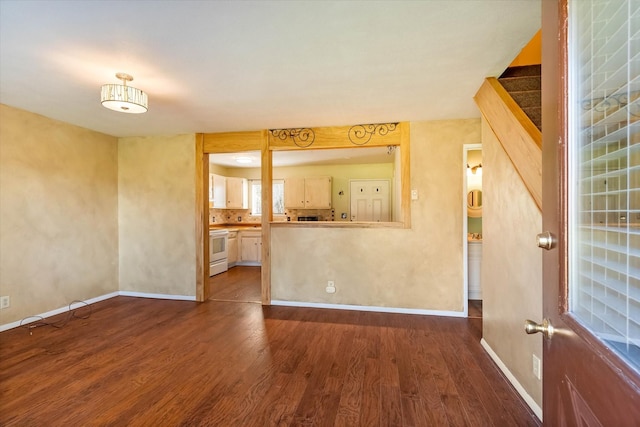 unfurnished living room featuring baseboards and wood finished floors