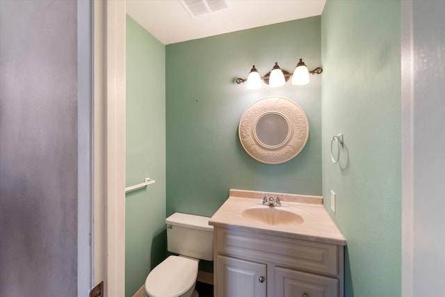 half bathroom featuring toilet, vanity, and visible vents