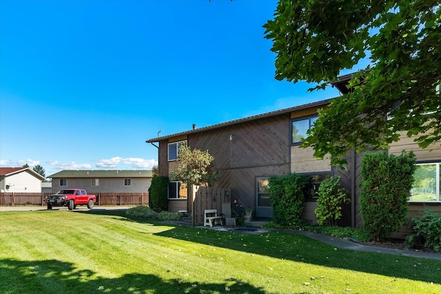 rear view of house with a yard and fence