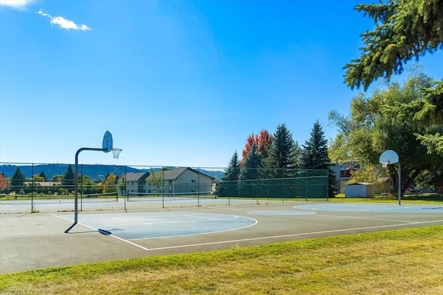 view of sport court with a lawn, community basketball court, and fence