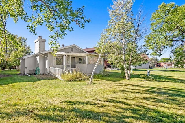 exterior space featuring a chimney, a porch, and a front lawn