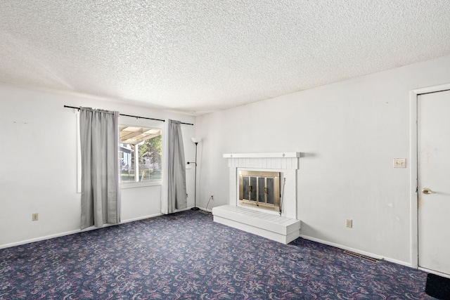 unfurnished living room featuring a brick fireplace, visible vents, baseboards, a textured ceiling, and carpet floors
