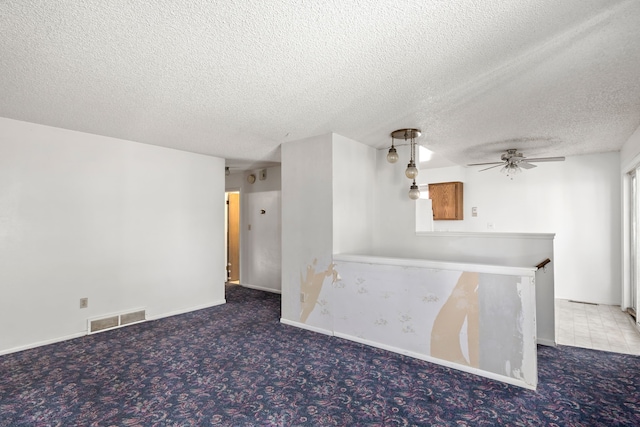 spare room featuring ceiling fan, a textured ceiling, and carpet