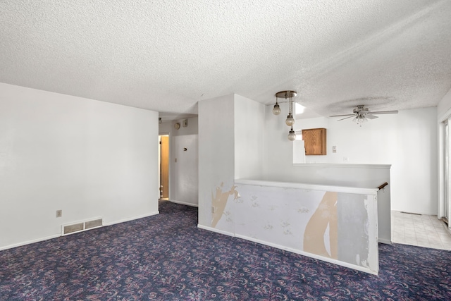 carpeted empty room featuring a textured ceiling, visible vents, and a ceiling fan