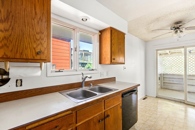 kitchen with light floors, black dishwasher, brown cabinets, ceiling fan, and a sink