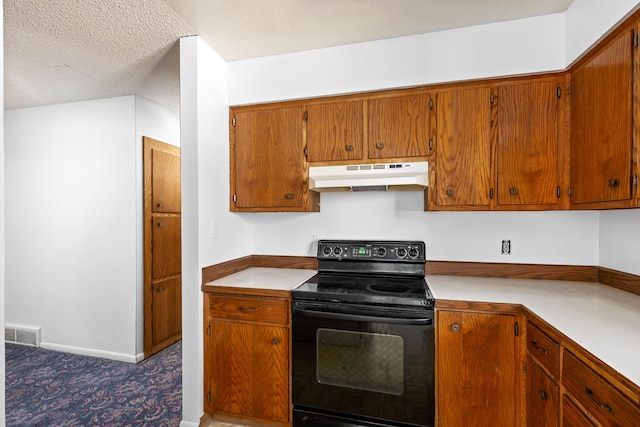 kitchen with under cabinet range hood, brown cabinetry, visible vents, light countertops, and electric range