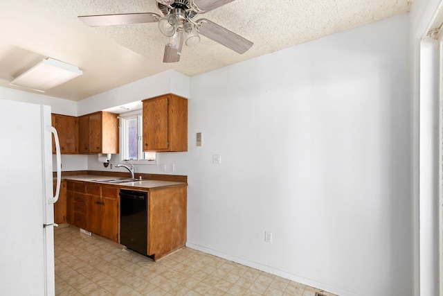 kitchen featuring brown cabinets, a sink, dishwasher, freestanding refrigerator, and light floors