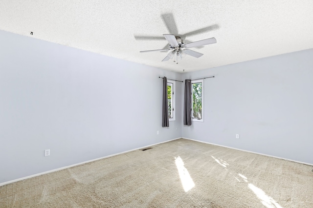 carpeted empty room with baseboards, visible vents, ceiling fan, and a textured ceiling