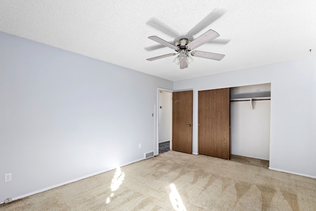 unfurnished bedroom featuring a textured ceiling, visible vents, ceiling fan, a closet, and carpet floors