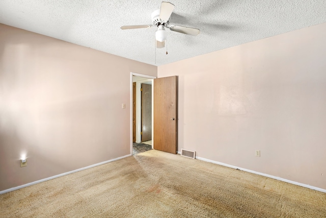 carpeted empty room with baseboards, visible vents, a ceiling fan, and a textured ceiling