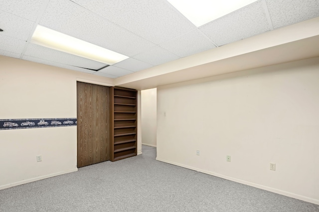 finished below grade area featuring baseboards, carpet floors, and a paneled ceiling