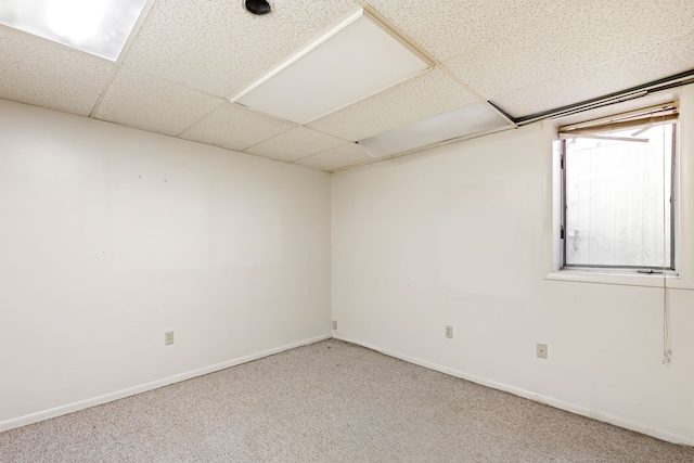 unfurnished room with a drop ceiling, carpet, and baseboards