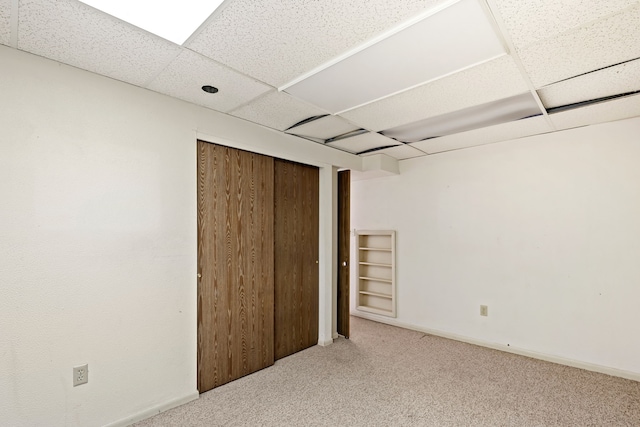 unfurnished bedroom with a drop ceiling, carpet, and a closet