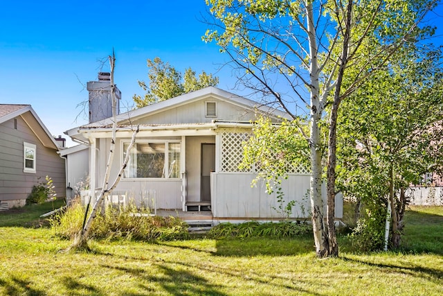 bungalow-style home featuring a chimney and a front yard
