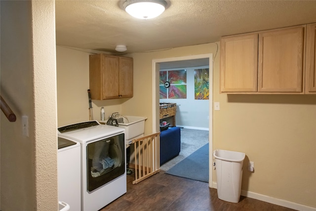 clothes washing area with cabinets, a textured ceiling, dark hardwood / wood-style floors, sink, and washing machine and dryer