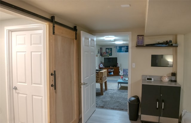 hall with light wood-type flooring and a barn door