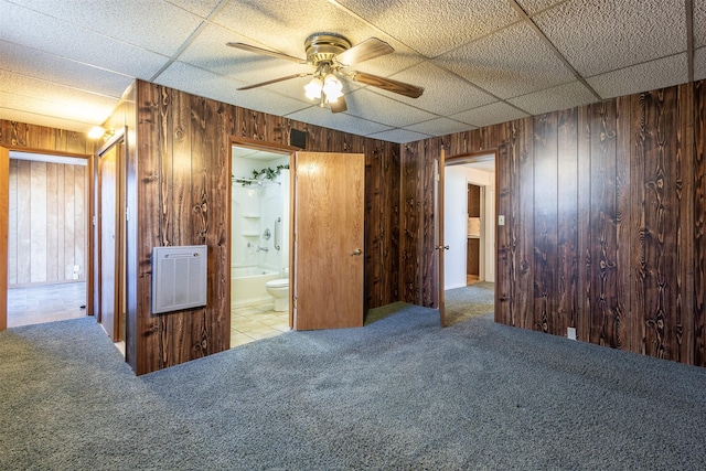 interior space with wood walls, ceiling fan, and heating unit