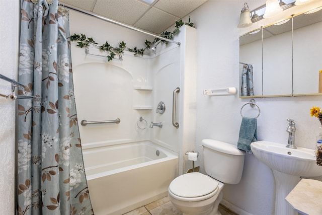 bathroom featuring tile patterned floors, shower / tub combo with curtain, toilet, a drop ceiling, and a sink