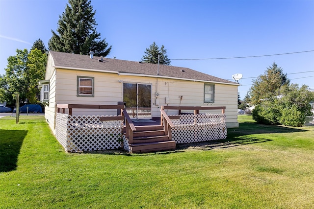 rear view of property featuring a yard, a wooden deck, and roof with shingles